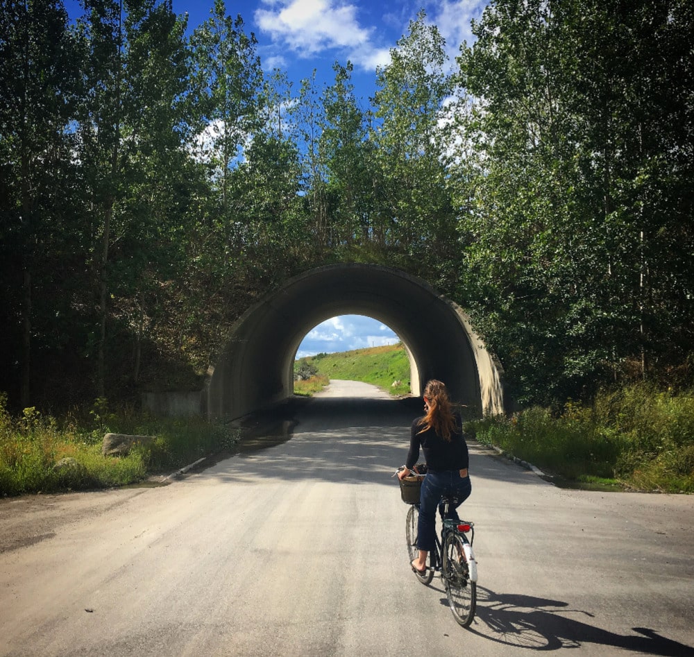 Ung kvinde cykler mod tunnel med lys for enden